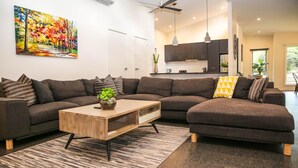 A modern living room with a sectional sofa, a wooden coffee table, and a colorful painting on the wall. - DECKED OUT AT BRIGHT : Bright (Bright)