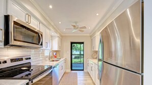 Una cocina moderna con electrodomésticos de acero inoxidable, muebles de cocina blancos y vistas al exterior.