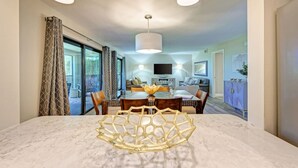 Un comedor moderno con una mesa de mármol, un centro de mesa decorativo y vistas al salón y al balcón.