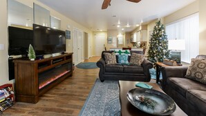 Ein Wohnzimmer mit Flachbildfernseher, Deckenventilator, Weihnachtsbaum und Kamin.