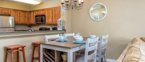 A kitchen with wooden cabinets, a stainless steel refrigerator, a microwave, and a chandelier.