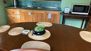 A round wooden dining table with placemats, a central potted plant, and a small card. - Heritage, renovated, miners Cottage in Clunes (Clunes)