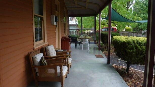 A covered porch with wooden furniture, a table, and chairs. - Heritage, renovated, miners Cottage in Clunes (Clunes)