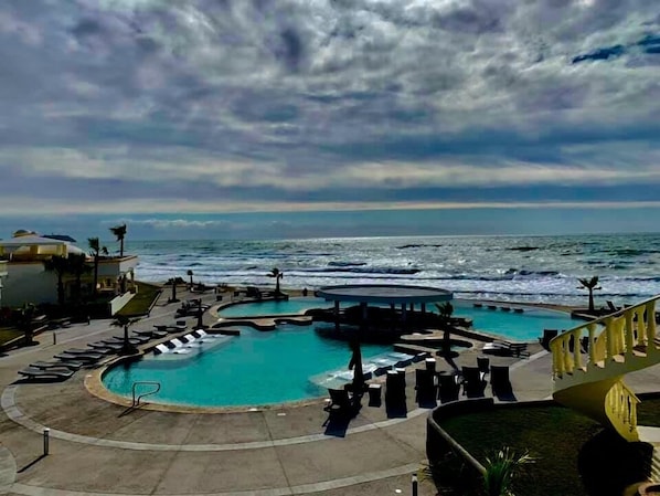 Relax by the ocean with a refreshing dip in the pool surrounded by lounge chairs and umbrellas.