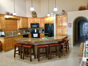 Fully equipped kitchen with island, pendant lights, and modern appliances.