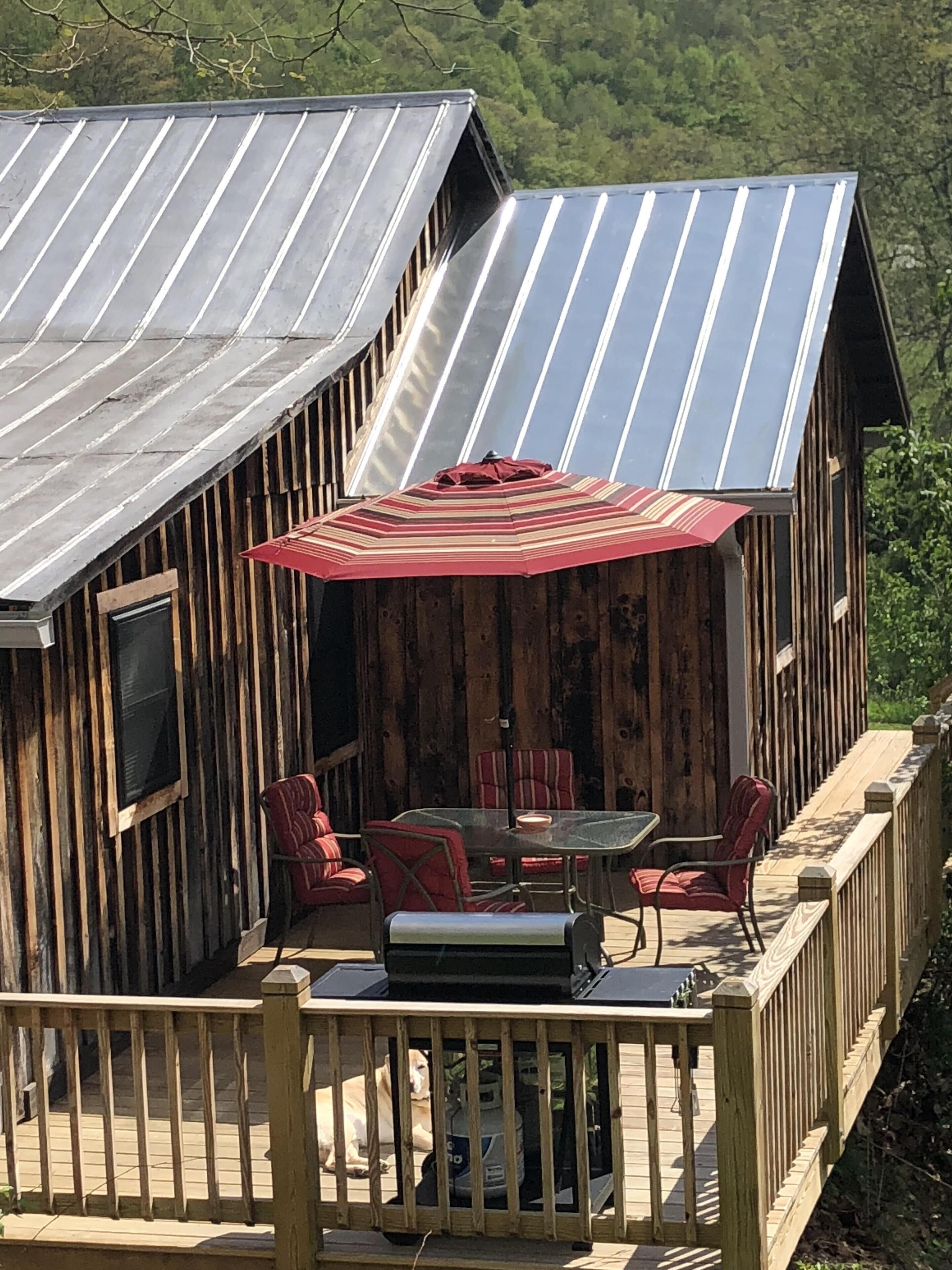 A wooden deck with a metal roof, outdoor furniture, and a large umbrella.