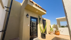 A building with a beige facade, black metal gates, and potted cacti. - Mazatlan Casita del Cielo with Pool (Mazatlán)