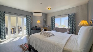 A hotel room with a bed, a desk, a chair, a fan, and a view of the city. - Mazatlan Casita del Cielo with Pool (Mazatlán)