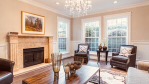 A spacious living room with a fireplace, large windows, and elegant furniture.