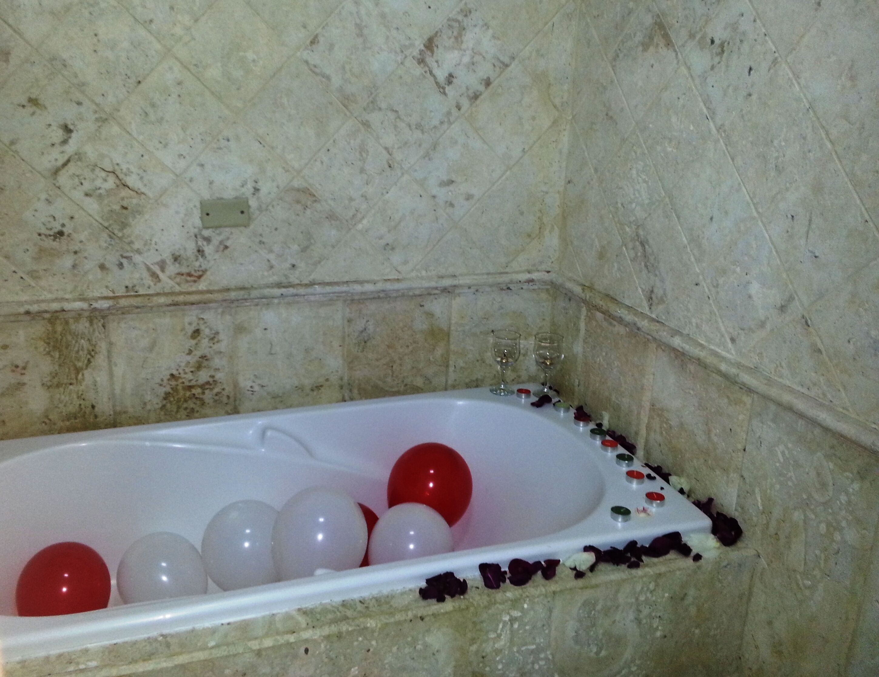 A bathtub with white and red bath balls, a white bathtub, and a tiled wall.