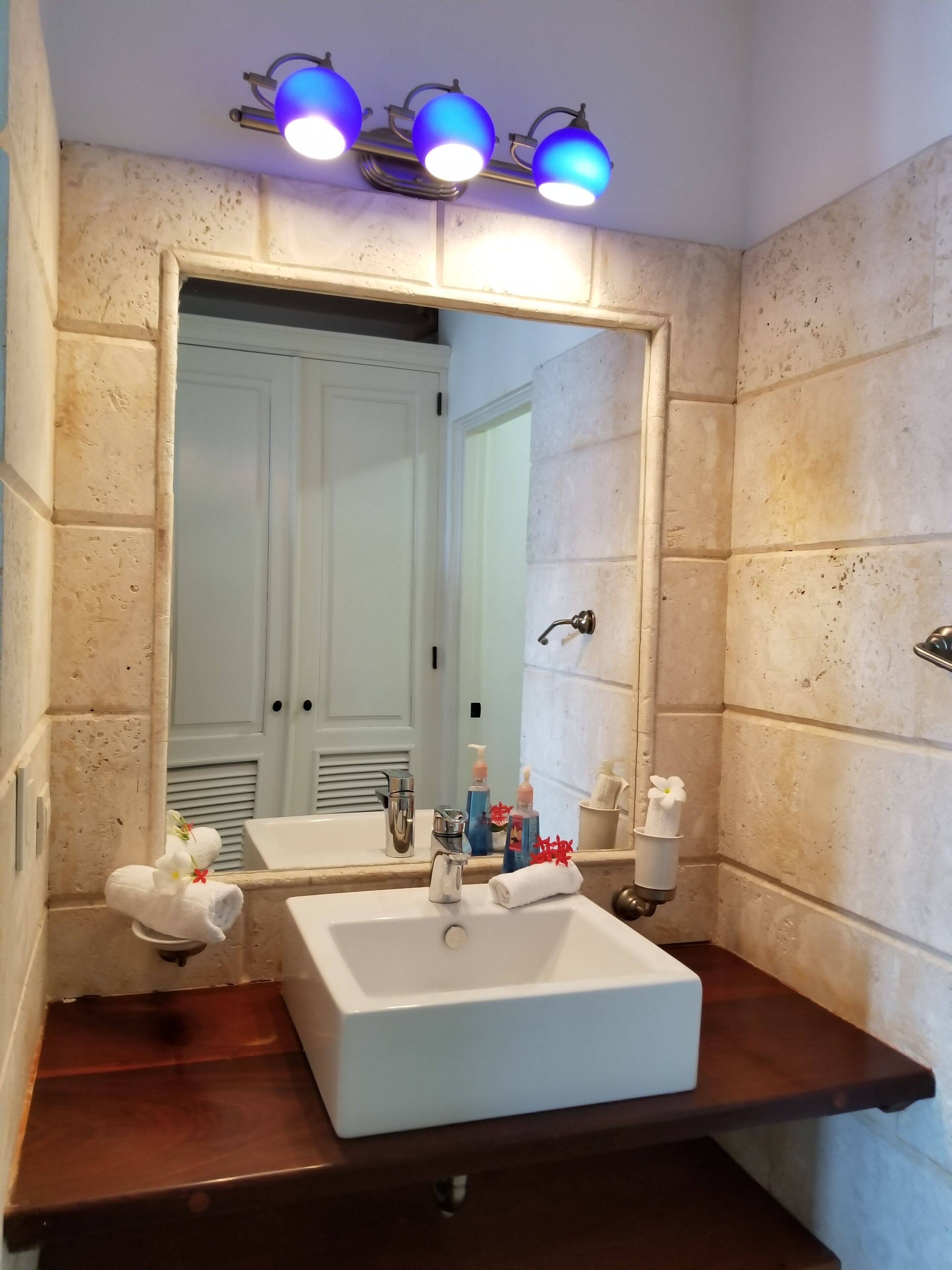 A bathroom with a white sink, a mirror, and a vanity with a towel rack.