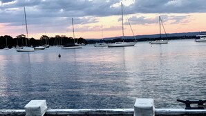 Ein Yachthafen mit mehreren Segelbooten, eine hölzerne Anlegestelle und eine ruhige Wasseroberfläche, die den Himmel spiegelt.