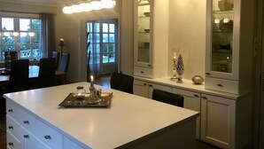 A modern kitchen with a central island, white cabinetry, and a dining area with a view of the outdoors. - Charming House with a Fantastic View of Norway's Nature (Ørsta)