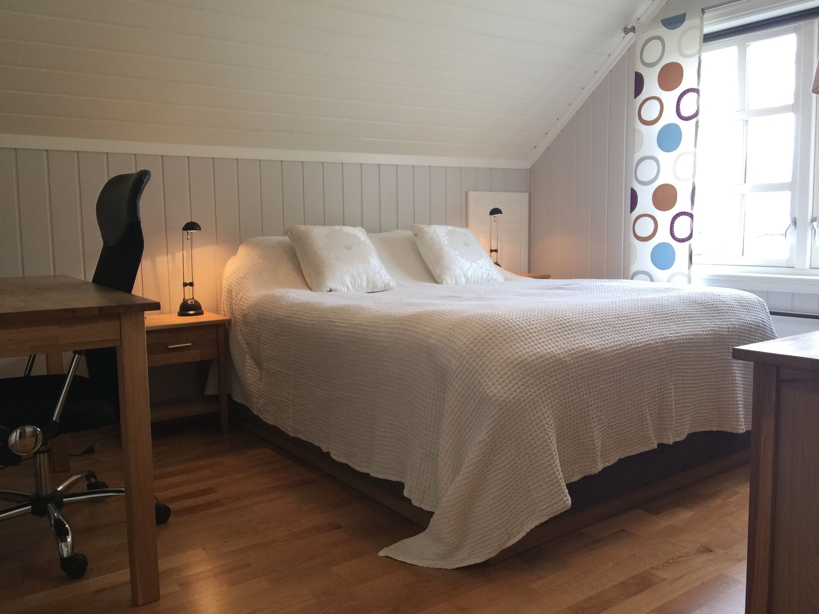 A bedroom with a bed, a desk, and a chair.