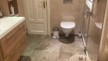 A bathroom with a white toilet, a sink with a mirror, wooden cabinets, and a tiled floor.