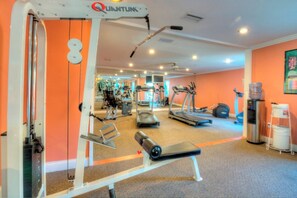 A gym with cardio machines, weightlifting equipment, and a mirrored wall. - Beach Club 207, Oceanfront complex (St Simons Island)