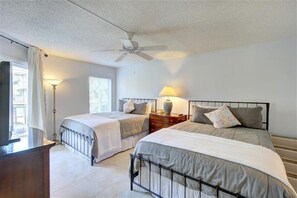 Une chambre avec deux lits, un ventilateur de plafond, des lampes de chevet et une table de chevet avec une lampe.