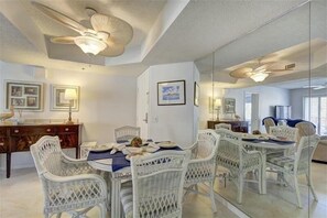 Un coin repas avec une table ronde, des chaises en osier blanches et des ventilateurs de plafond.