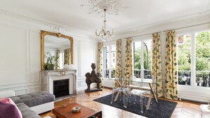 A spacious living room with a fireplace, a large mirror, and a view of the outdoors. - CAVALIER DES LIONS 2bedr 2 1/2baths (Paris)