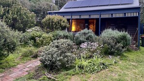 A house with solar panels on the roof, surrounded by various plants and shrubs. - Lavender Cottage Venus Bay (Venus Bay)