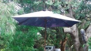 An outdoor wooden deck with a table and chairs, a grill, and a large umbrella. - Lavender Cottage Venus Bay (Venus Bay)