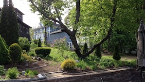 A garden with a stone retaining wall, a metal table, and chairs.