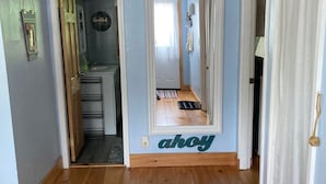 A hallway with wooden flooring, a door leading to a bathroom, and a sign on the wall.