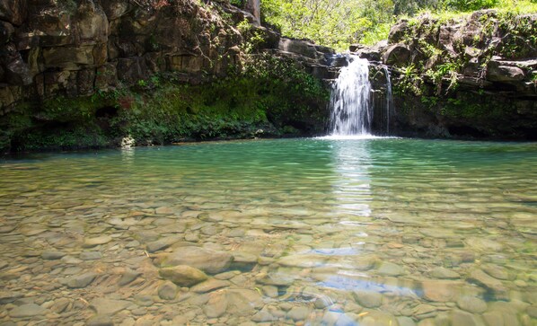 A clear, rocky pool with a waterfall.