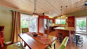 A spacious kitchen with wooden ceiling, a dining area with a table and chairs, and a view of greenery outside. - Luxury 3BR Wailea Kihei Retreat. Walk to Beaches, Private Lanai, Newly Remodeled (Kihei)