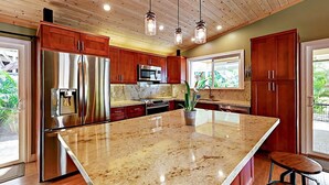 A modern kitchen with wooden cabinets, stainless steel appliances, and a large island. - Luxury 3BR Wailea Kihei Retreat. Walk to Beaches, Private Lanai, Newly Remodeled (Kihei)