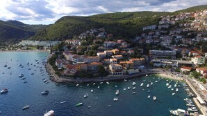 A coastal town with buildings clustered along the waterfront, boats in the water, and a hilly backdrop. - Villa 5 stars , Istra , Croatia (Sveta Nedelja, Istarska županija)