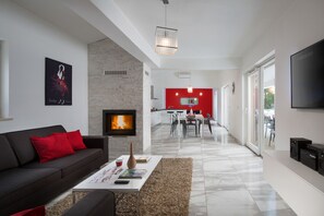 Relax in this stylish living space with a cozy fireplace, comfortable sofa, and functional dining area.