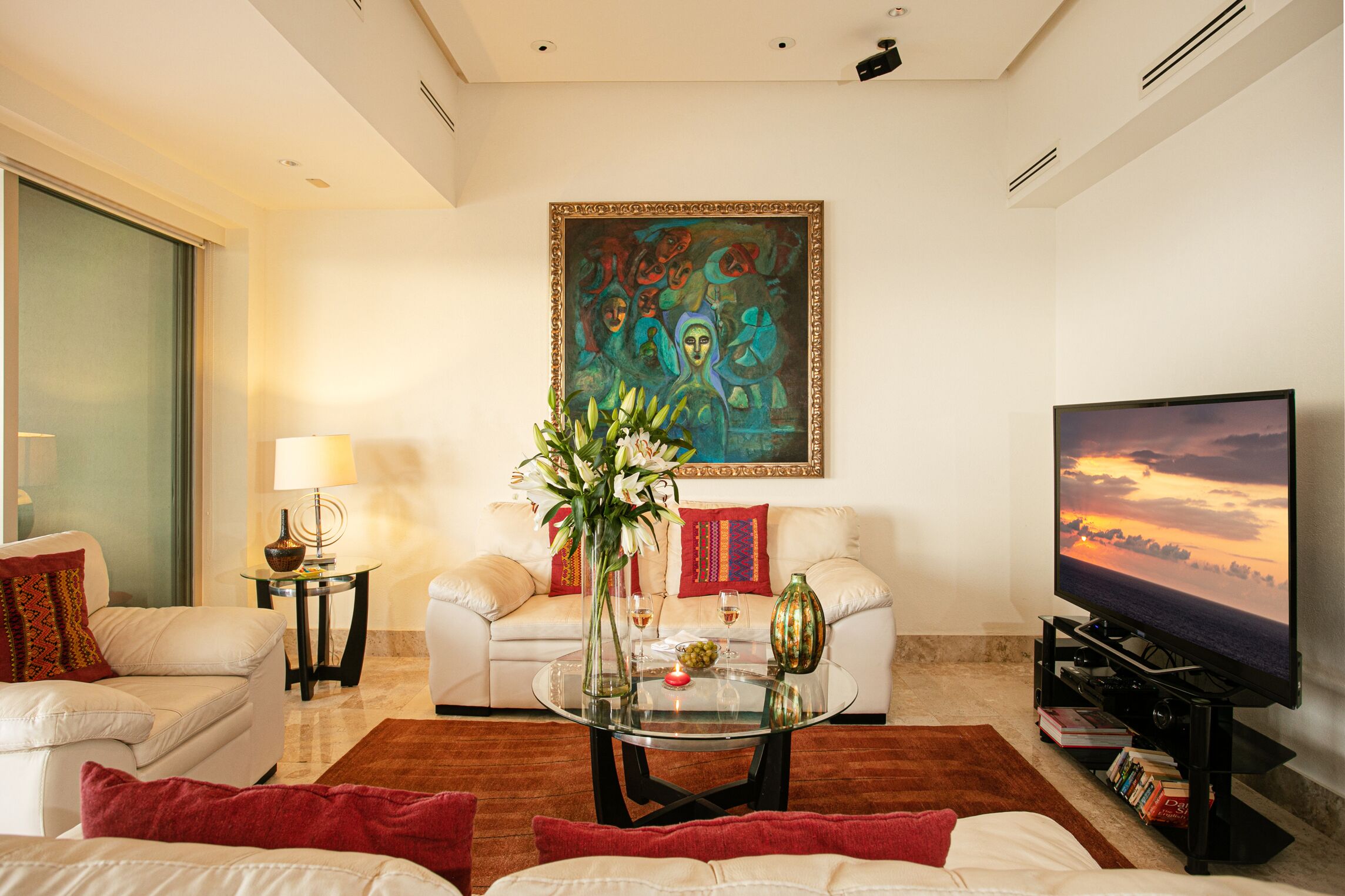 A living room with a sofa, a coffee table with a vase, a painting on the wall, and a TV on a stand.