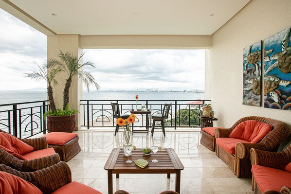 A balcony with wicker furniture, a table with drinks, and a view of the sea. - Panoramic Oceanview, Luxury Condo 3 bd, 3bath on the beach. (Puerto Vallarta)