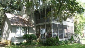 A two-story house with a porch, large windows, and a well-maintained lawn. - Chechessee River House (Okatie)