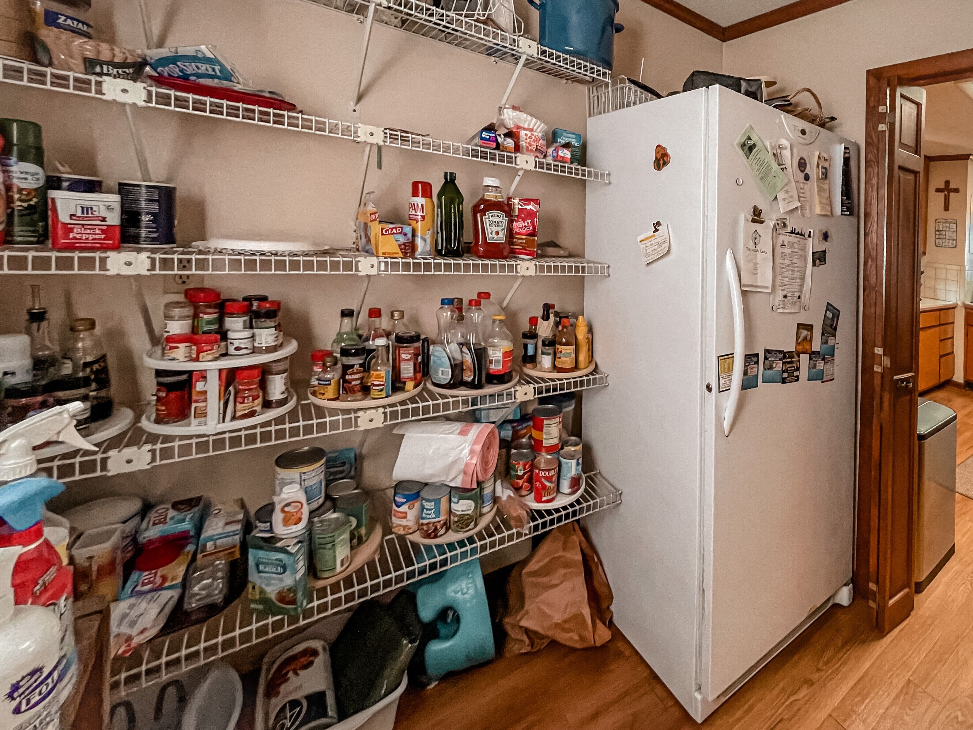 A kitchen with multiple shelves stocked with various food items and condiments.