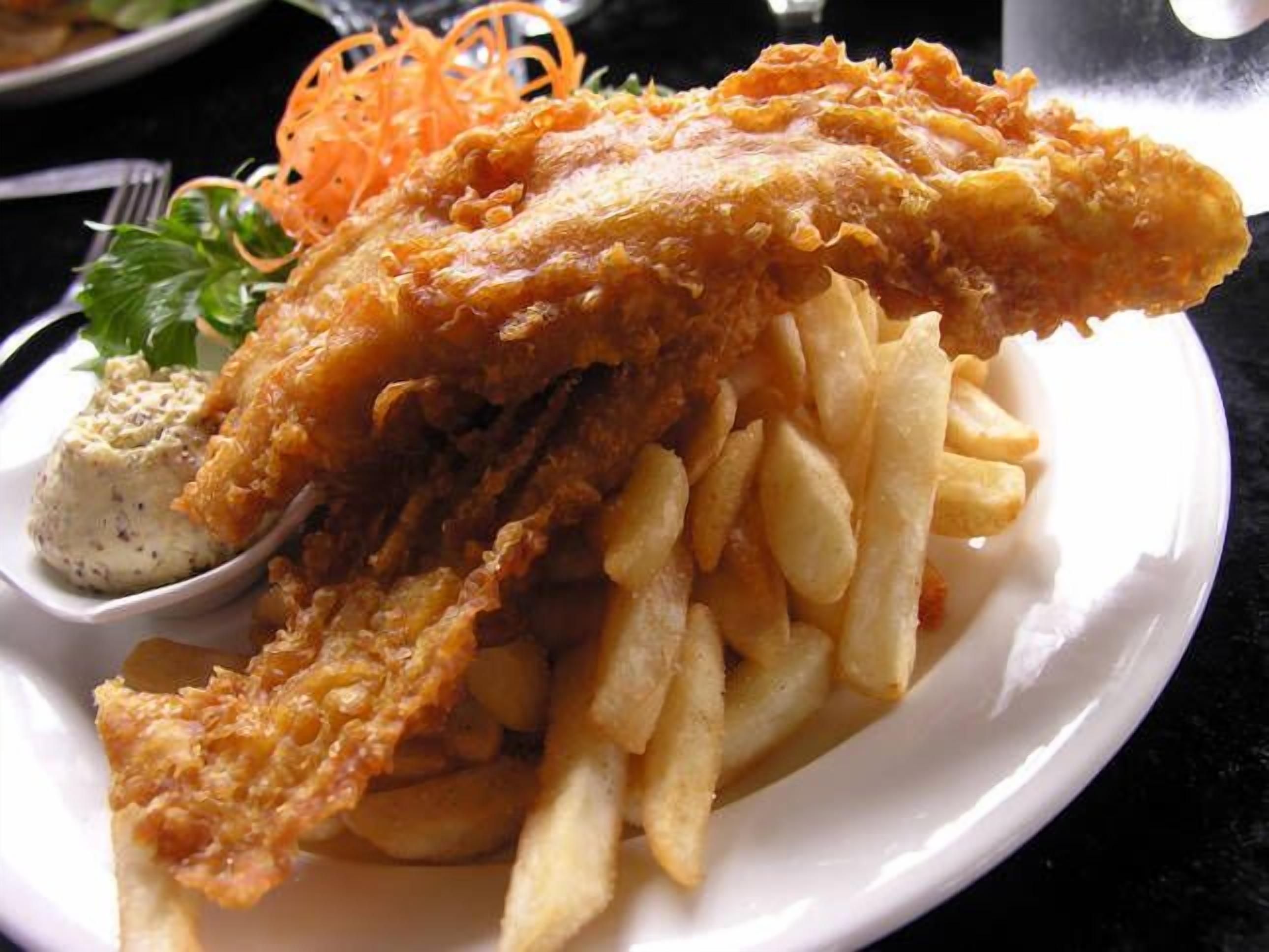 Ein Teller Fish and Chips mit Pommes und einer Portion Tartarsauce.