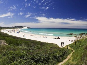 A beach with a clear sky, people relaxing, and a path leading to the beach. - Unwind & Relax @ Forster (Forster)