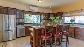 Una cocina moderna con armarios de madera, electrodomésticos de acero inoxidable y una isla central con taburetes de bar.
