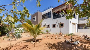 Un edificio moderno de dos pisos con fachada blanca, ventanas amplias y un balcón.