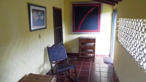 A room with a tiled floor, a chair, a small table, a wall-mounted shelf, and a framed picture. - Spacious in-suite room Bo. Herrera, Asuncion (Asunción)