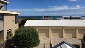 A building with a flat roof, multiple garage doors, and a view of the sea in the background. - Dare St Beach Apartment | 2-Min Walk to Beach & Town (Ocean Grove)