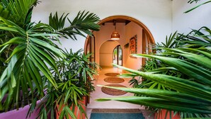 Um corredor com teto de madeira, arcos e plantas em vasos.