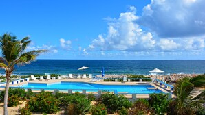 A pool area with lounge chairs and umbrellas, overlooking the ocean. - Seaside Splendor:  2-3 BR w/ Expansive Deck, Panoramic Views, AC, Wifi, & Pool (Sandy Hill Bay)