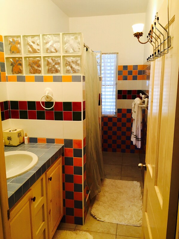 A bathroom with a tiled floor, a sink, a toilet, and a shower area. - Seaside Splendor: 2-3 BR w/ Expansive Deck, Panoramic Views, AC, Wifi, & Pool (Sandy Hill Bay)