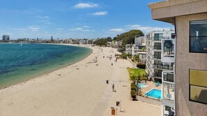 Um hotel à beira-mar com piscina, praia de areia e vista para o oceano.