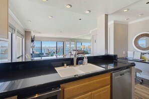 A modern kitchen with a black countertop, stainless steel appliances, and a view of the city.