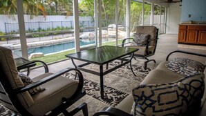 A sunlit patio with a pool view, outdoor furniture, and a kitchen area. - Oasis in the heart of Equestrian country (Wellington)