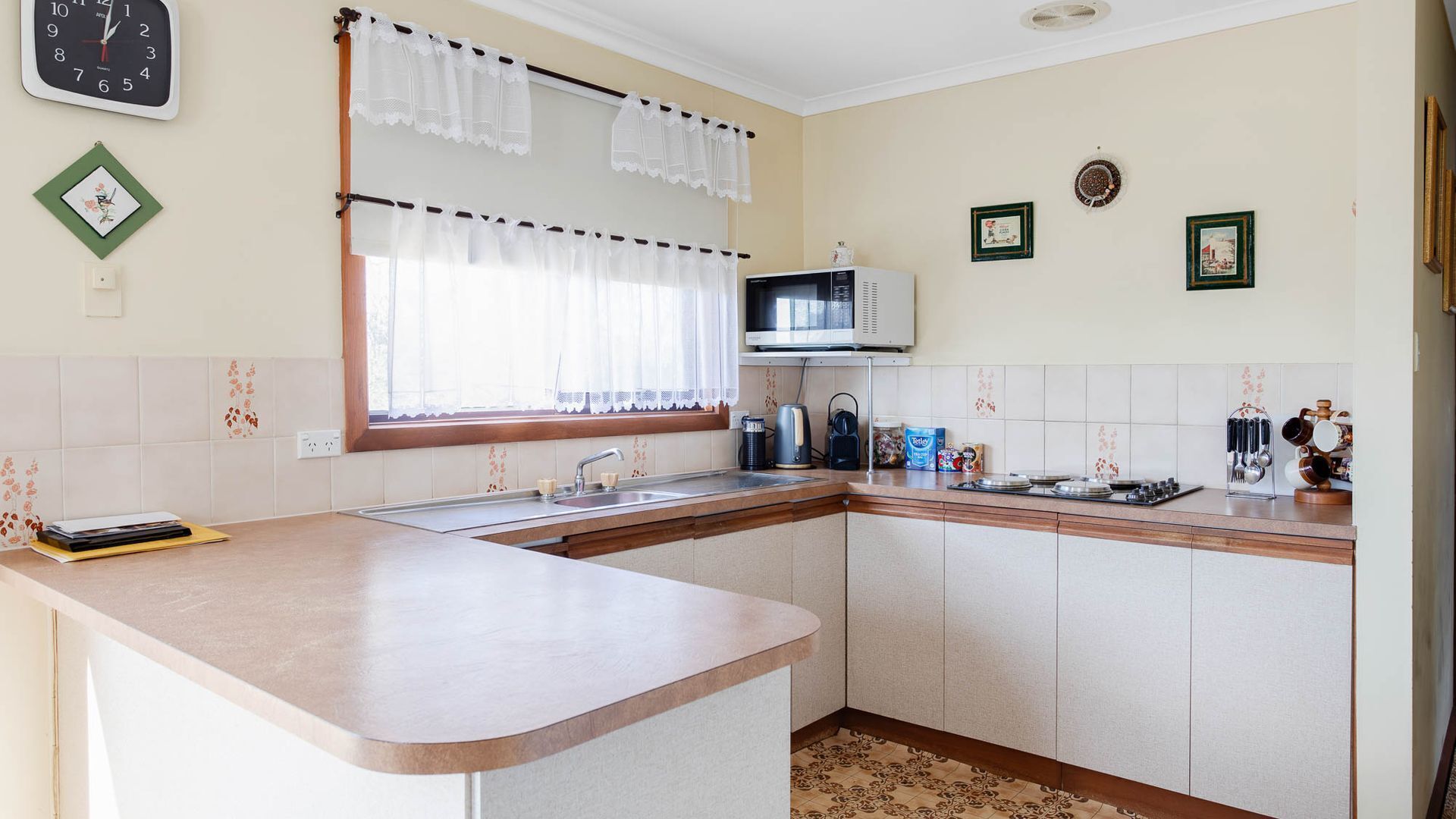 A kitchen with a sink, stove, microwave, and various kitchen items.