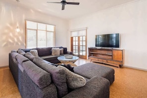 A living room with a sectional sofa, a television, and a ceiling fan.